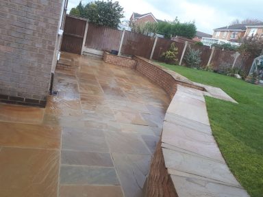 Patio area with a curved stone pathway and landscaped garden in the background.