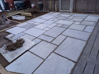 Paved outdoor area with variously sized concrete slabs on a dirt foundation.