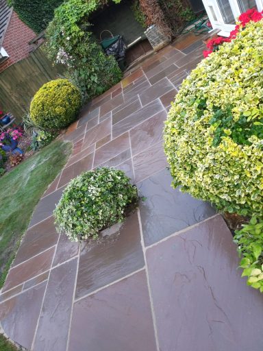 Stone pathway bordered by neatly trimmed bushes and colourful flowers.