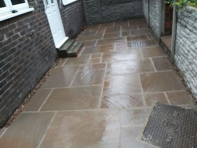 Paved pathway with light-coloured stones, leading to a white door.
